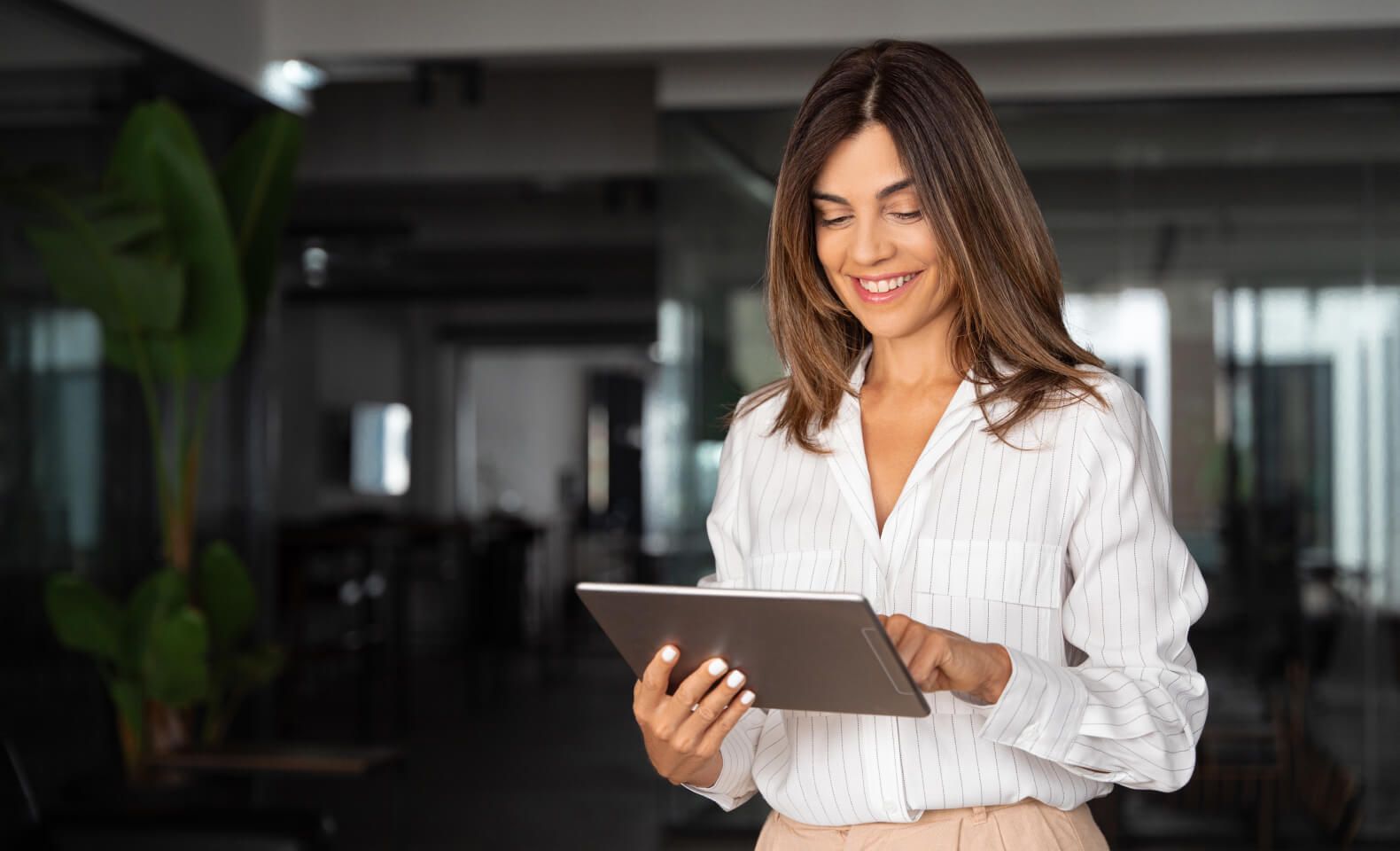Smiling woman using a digital tablet in a modern office setting – Neutrinos