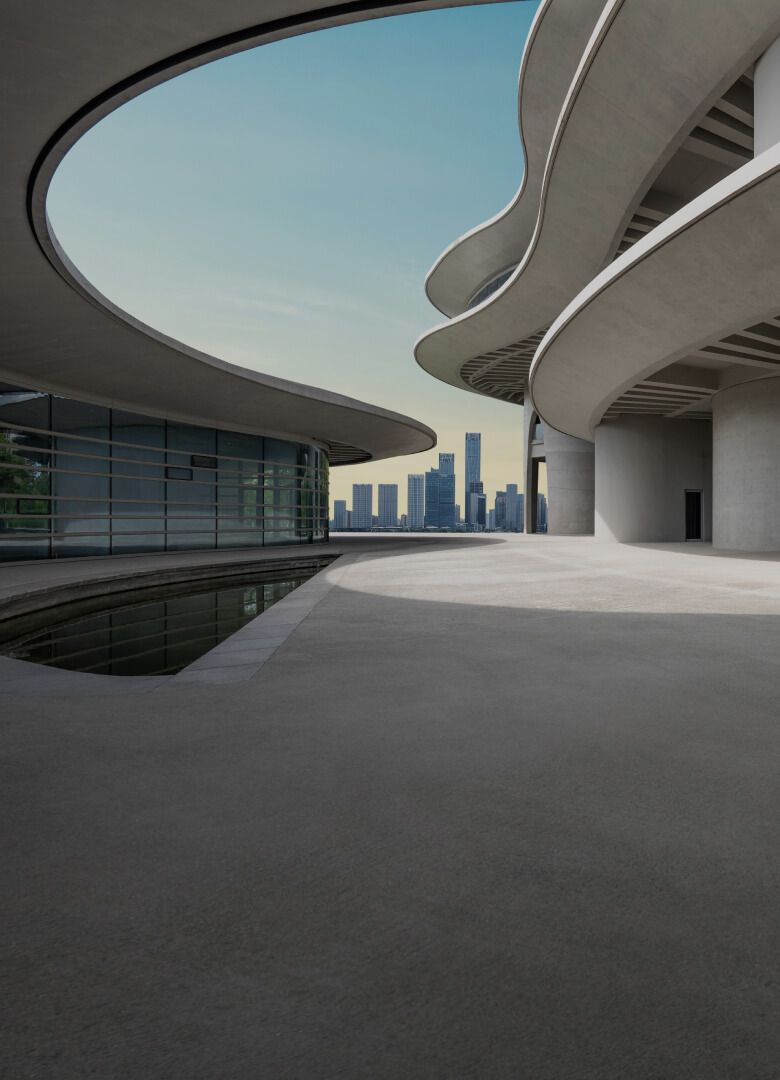 Modern architectural structure with curved concrete overhangs and a city skyline in the background.-Neutrinos
