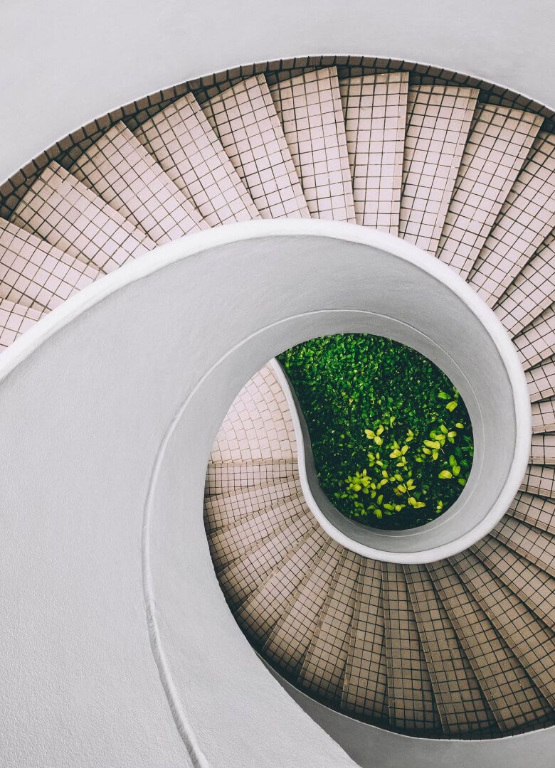 Top view of a spiral staircase with tiled steps and a lush green garden at the center- Neutrinos