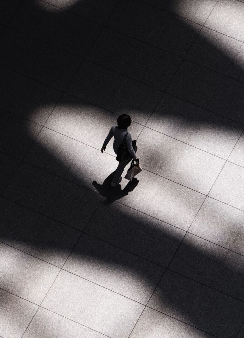 Woman walking alone across tiled floor with dramatic lighting-Neutrinos