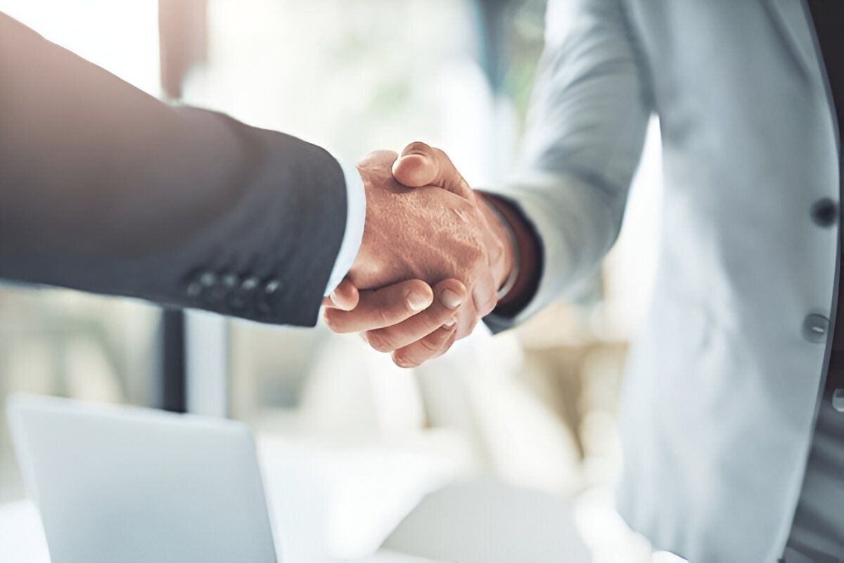 Close-up of two business professionals shaking hands in a formal setting, symbolizing partnership or agreement-Neutrinos