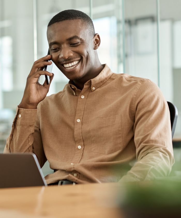 Smiling professional on a phone call while working on a laptop at a modern office - Neutrinos