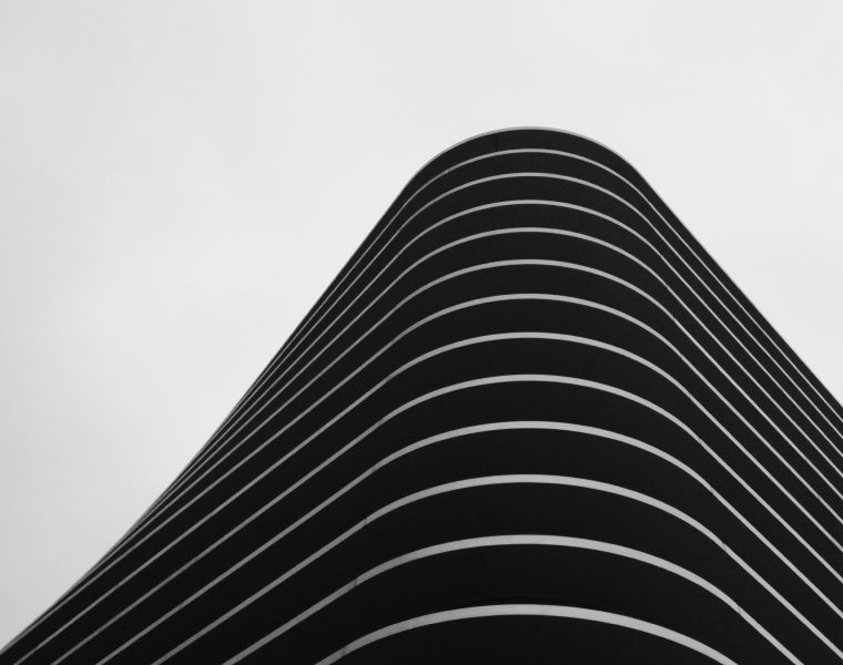 Minimalist black and white view of a curved modern building with horizontal lines-Neutrinos