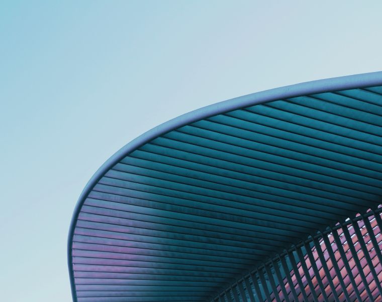 Modern curved roof with parallel beams against a pastel sky, showcasing futuristic design - Neutrinos