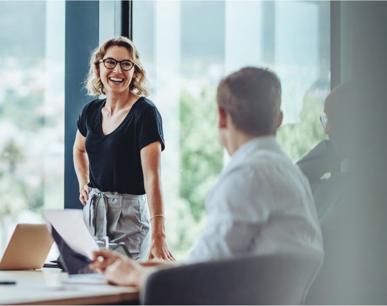 Smiling professional engaging in team discussion in a modern glass-walled office – Neutrinos