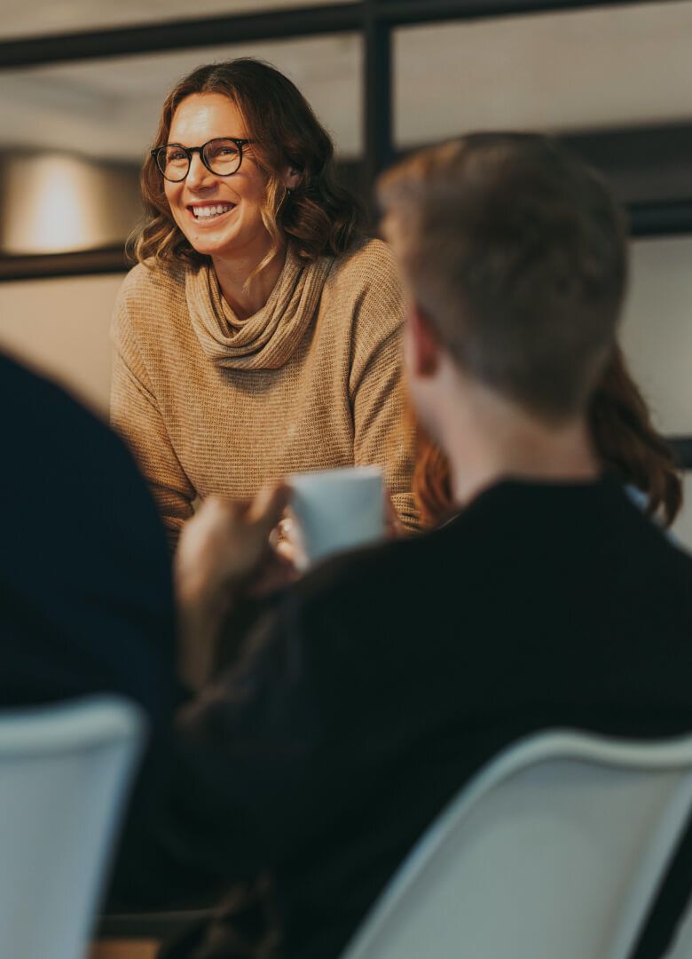 Smiling woman leading a casual team discussion in office-Neutrinos