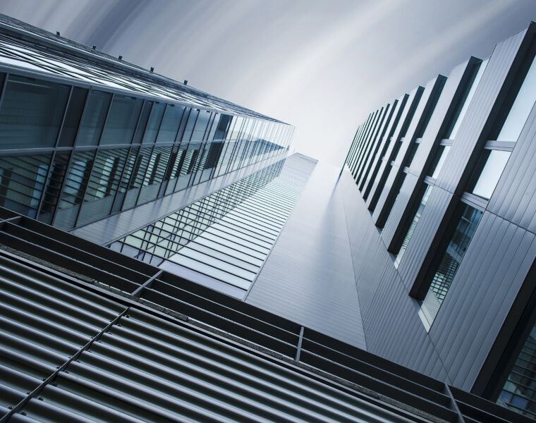 Low-angle view of tall glass skyscrapers converging toward the sky - Neutrinos