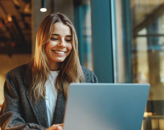 Smiling woman using a laptop in a modern office or café setting-Neutrinos