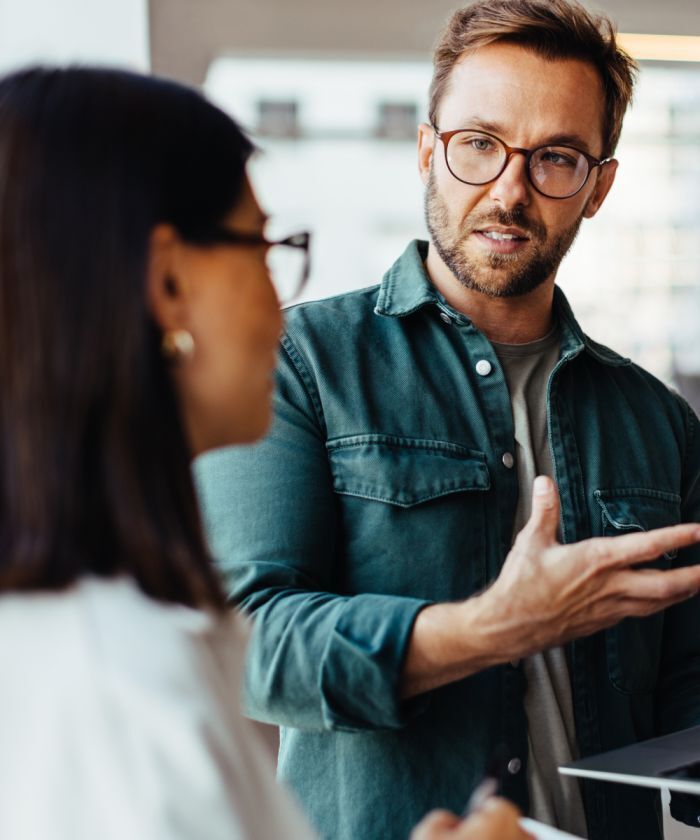 Young professional man in glasses explaining a concept to a colleague during a workplace discussion- Neutrinos