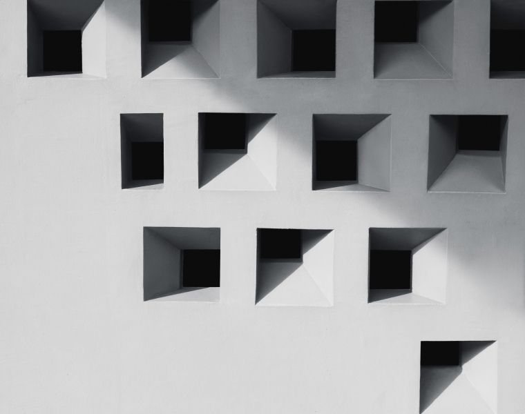 Modern architectural wall with geometric square recesses casting deep shadows, showcasing minimalist design pattern- Neutrinos