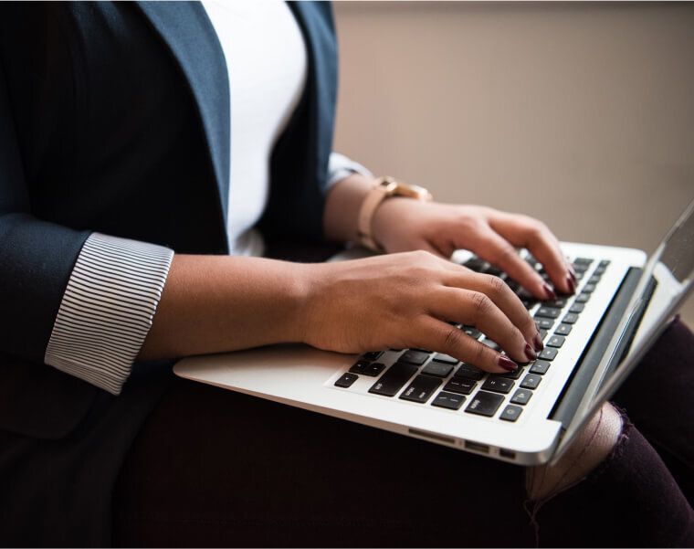Close-up of a woman typing on a laptop, seated with hands resting on the keyboard-Neutrinos