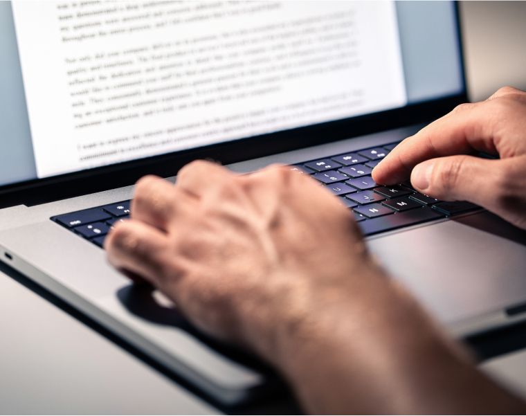 Close-up of hands typing on laptop keyboard with document editing on screen – Neutrinos
