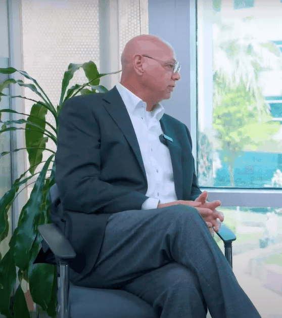 Executive in a suit seated in an office setting – Neutrinos.